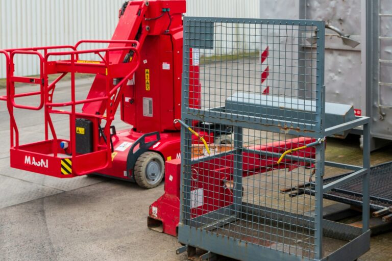 Red articulated boom lift with basket and metal cage