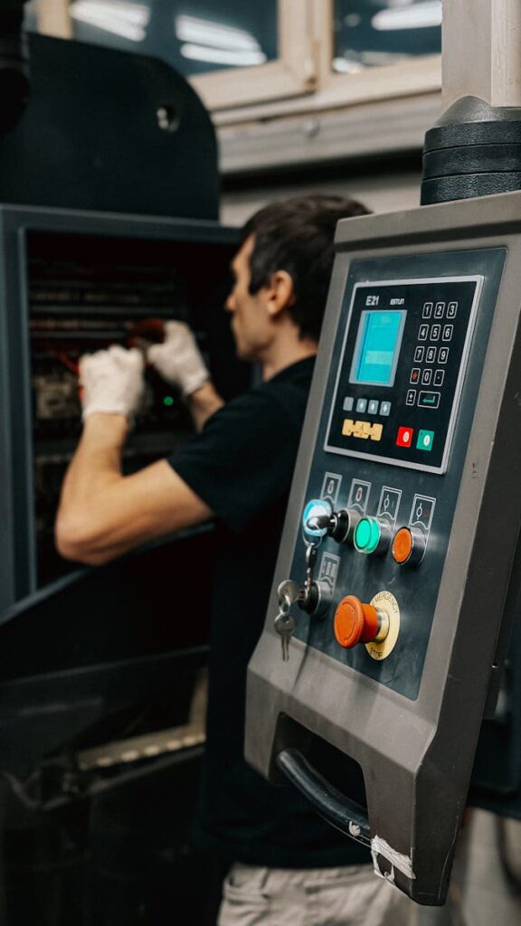 Ursachen und Gegenmaßnahmen bei ungeplanten Maschinenstillständen in der Fertigung Technician using a control panel to manage machinery operations in a factory.